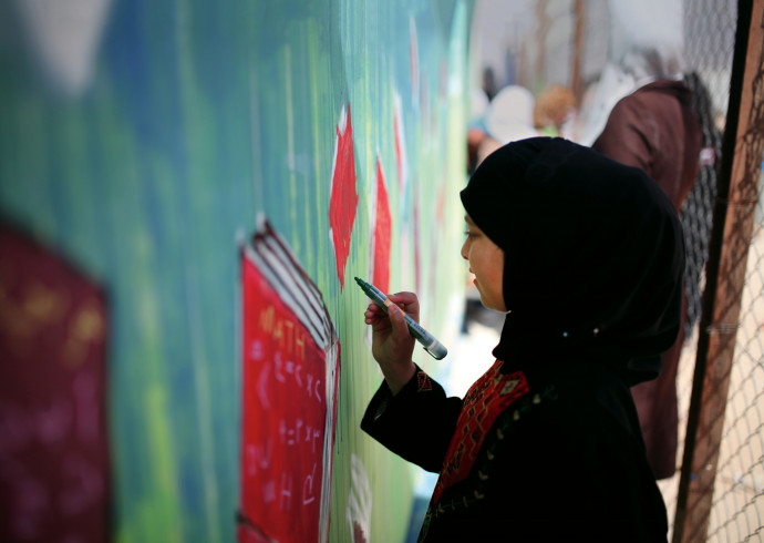 A young Syrian refugee paints a street mural as part of an aptART workshop in the Zaatari refugee camp in Jordan (Photo by Samantha Robis...