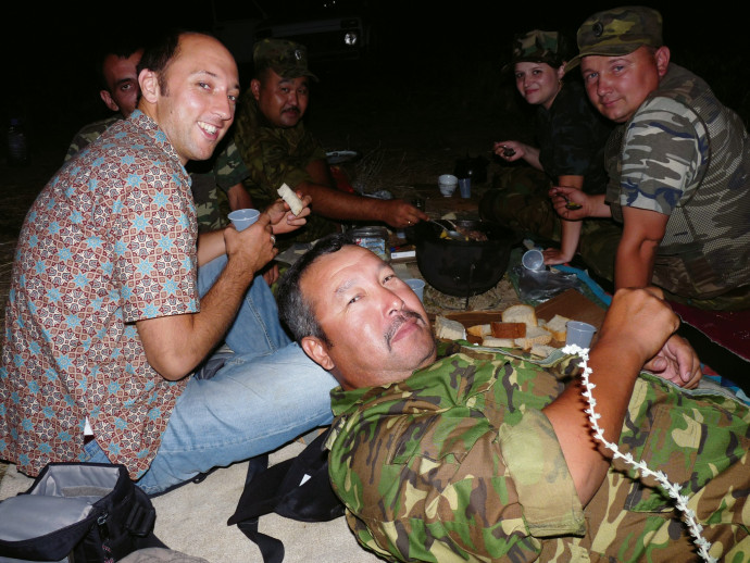 Carl Schreck BA '98 eating wild rabbit stew with officers from the Interior Ministry of Kazakhstan; they were taking a break from track...