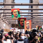 Thousands of protesters walk in a peaceful protest across the Brooklyn Bridge holding signs that ...