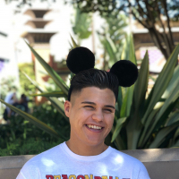 Julian smiling at the camera wearing black Mickey Mouse ears.