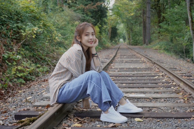 Evangeline, sitting on railroad tracks, smiling into the camera.