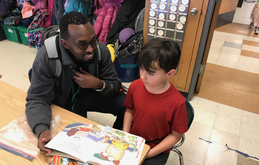Fabrice helps a first-grade student with his reading.