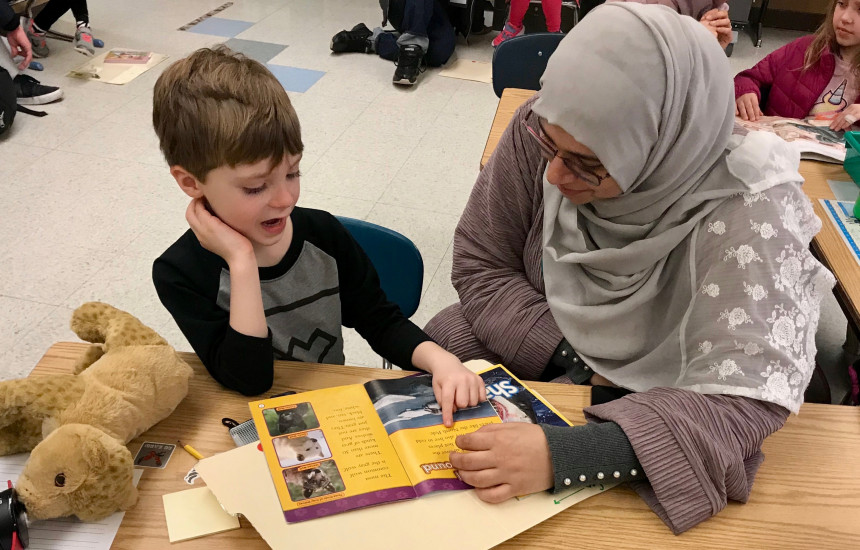 Omnia helps a first-grade student with his reading.