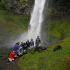 Image shows a group of people in front of a waterfall