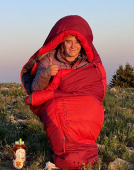 Athena in bright red sleeping bag with thumbs up