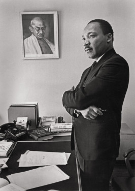 Martin Luther King Jr. in his SCLC office. On the wall is a portrait of Mahatma Gandhi, whose practice and teaching of nonviolent direct action inspired King's work. King asked Bob Fitch to photograph him here for the jacket of his then-forthcoming (and last) book, Where Do We Go From Here? published in 1967. This image is also the basis for the Martin Luther King Jr. Memorial in Washington, D.C., unveiled in 2011. Atlanta, Georgia, 1966.
