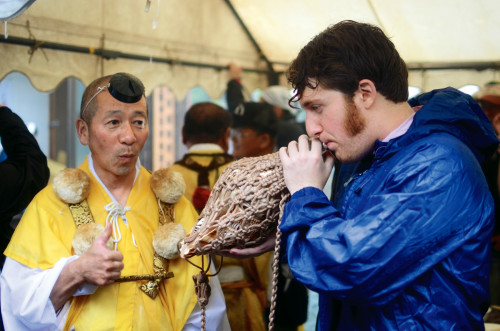 Joshua Proto learns how to blow a ritual conch at a ceremony