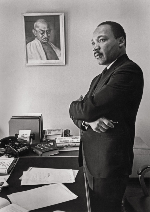 Martin Luther King Jr. in his SCLC office. On the wall is a portrait of Mahatma Gandhi, whose practice and teaching of nonviolent direct ...