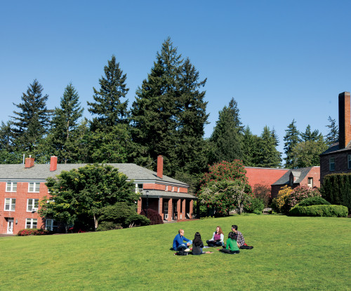 Students sitting in a circle on the lawn at the graduate school.