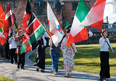 A diverse group of Lewis & Clark students carry colorful flags from several countries: intern...
