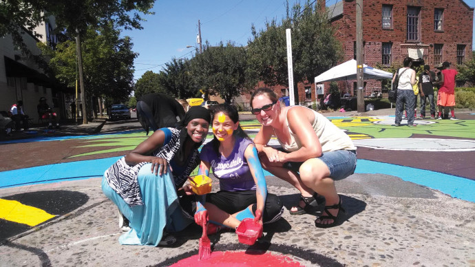 Kallie Kurtz (far right) works with teens painting a street mural for peace.