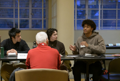 Students sitting at a table speaking to a business mentor.