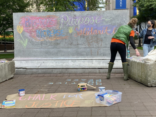 LC Art for Social Change members Mary Andrus, and Liv Siulagi draw with colored chalk at Shemansk...