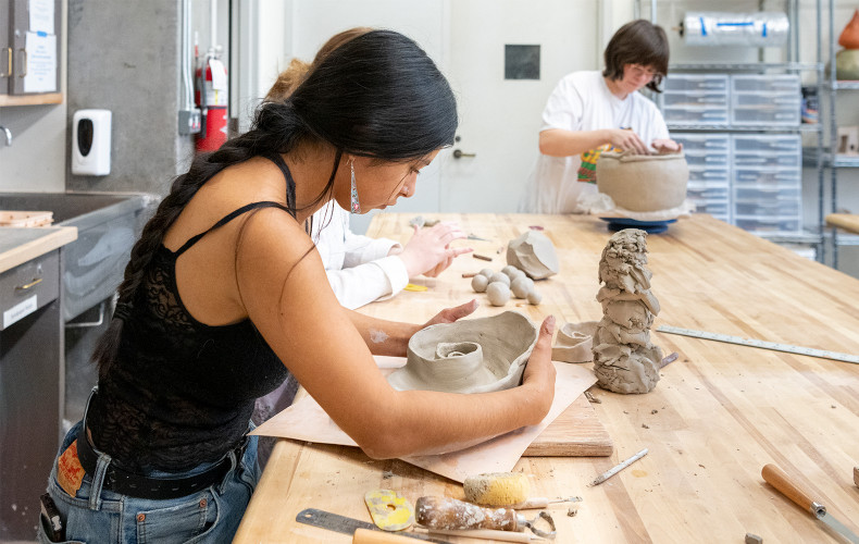 Student molding a bowl out of clay with their hands.