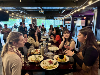 Students and alumni talking at a table over food and drinks.