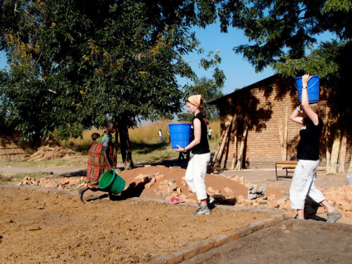 Katie Keith '15 and Anna Lofstrand '13 carry water from the well to the worksite to help mix cement.