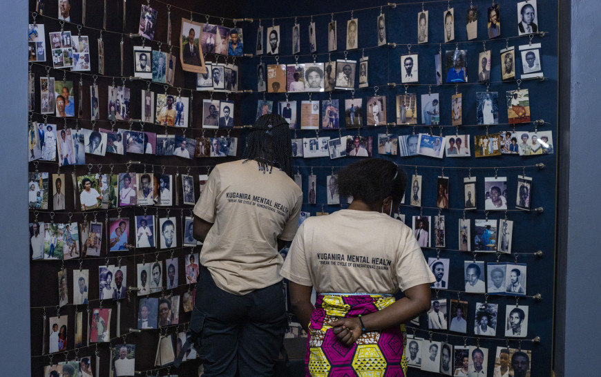 Participants looking at a wall hung with tons of images of genocide victims.
